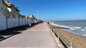 Eine Uferpromenade mit weißen Strandkörben und einem Sandstrand.