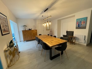 Ein Essbereich mit Holztisch, schwarzen Stühlen, einem Holzschrank, einem kleinen Weihnachtsbaum und einem Bild an der Wand.