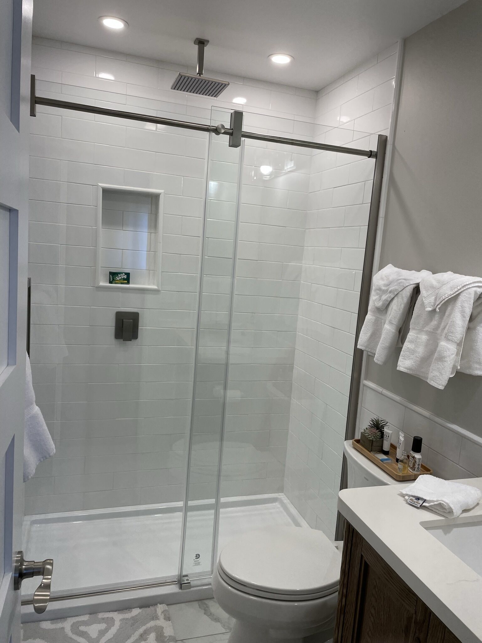 Un baño moderno con ducha de vidrio, inodoro y tocador con perchero.