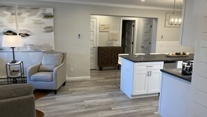 A modern kitchen with white cabinets, a granite countertop, and a dining area with a chair. - Newly renovated 4BR & 3BR condo walk to slopes (Snowshoe)