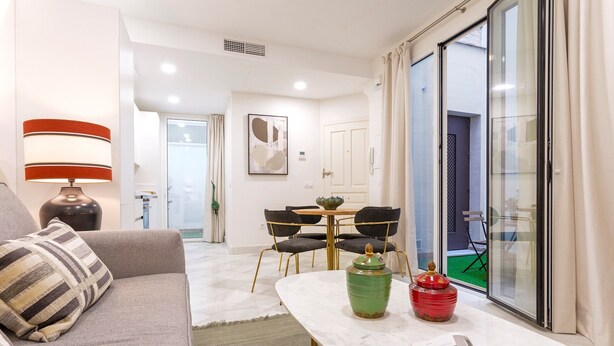 Uma sala de estar moderna com sofá, mesa de centro e área de jantar com cadeiras e mesa.