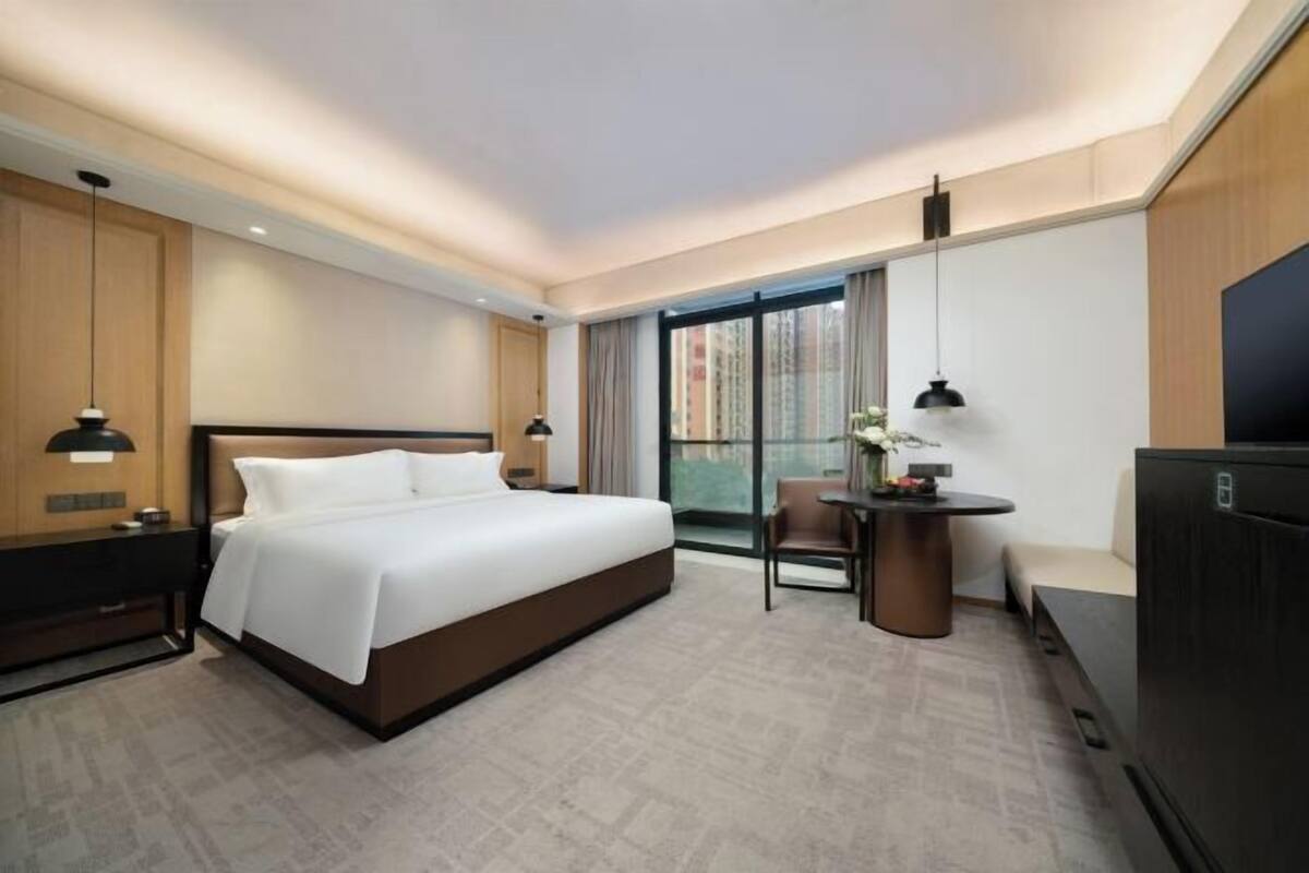 A modern hotel room with a large bed, a desk, and a TV.