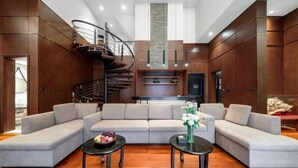 A modern living room with a sectional sofa, a spiral staircase, and a fireplace. - Guigang Railway Station UEASY Hotel (Guigang)