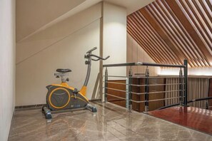 A modern interior with a stationary exercise bike, a wooden slatted ceiling, and a metal railing. - UEASY Hotel (Guigang National Cultural Park High Speed Railway Station) (Guigang)