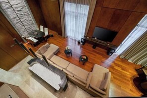 Uma sala de estar moderna com sofá seccional, televisão e área de refeições com mesa e cadeiras.