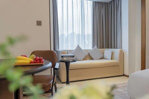 A hotel room with a sofa, a small table with fruits, and a book titled "Cinderella". - UEASY Hotel (Guigang National Cultural Park High Speed Railway Station) (Guigang)