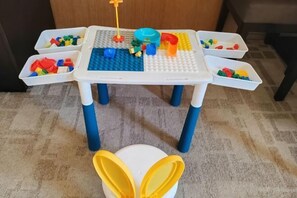 A table with a white base and blue legs, holding various colorful building blocks and a toy in the center. - UEASY Hotel (Guigang National Cultural Park High Speed Railway Station) (Guigang)