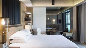 A hotel room with a large bed, a desk with a chair, a bookshelf, and a dining area with a table and chairs. - Guigang Railway Station UEASY Hotel (Guigang)
