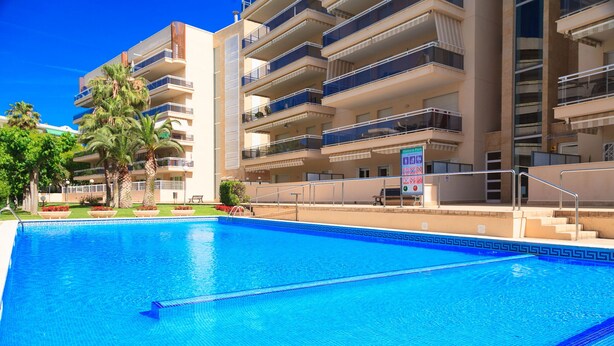 Piscina com água azul cristalina, rodeada por um edifício de vários andares com varandas.