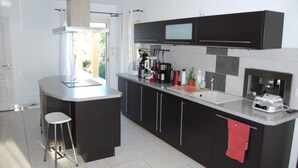 A modern kitchen with a central island, black cabinets, and stainless steel appliances. - Bright villa - Private pool - Near Pézenas (Valros)