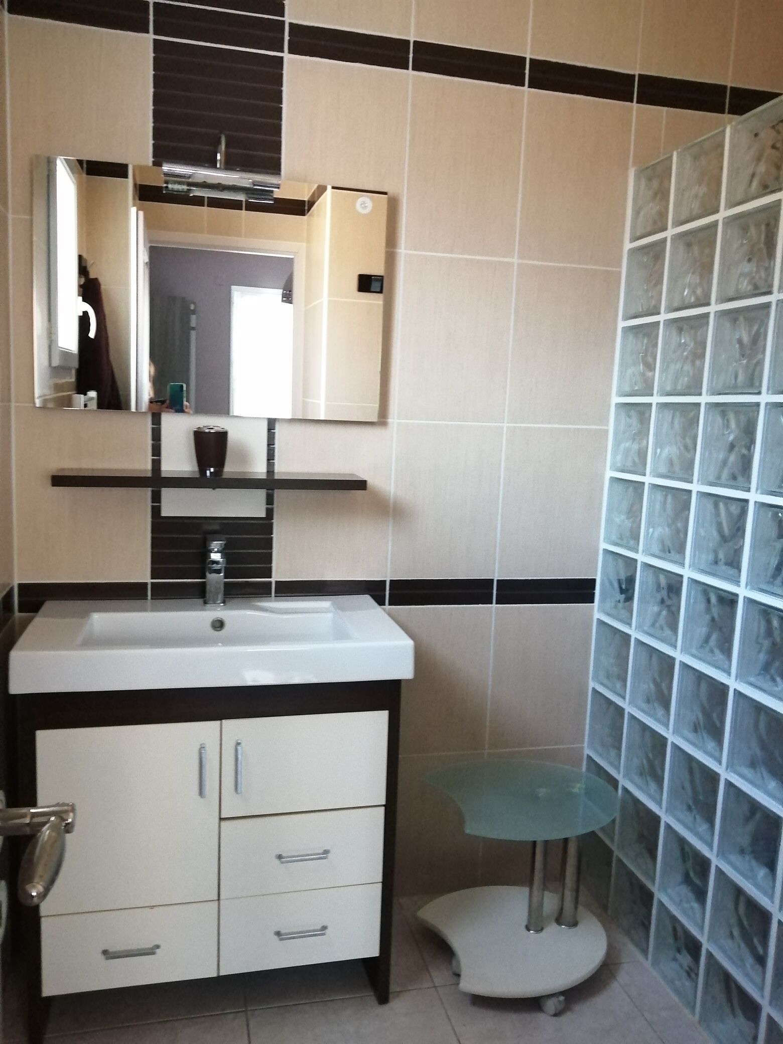 A bathroom with a white sink, a mirror above it, and a glass shower enclosure.