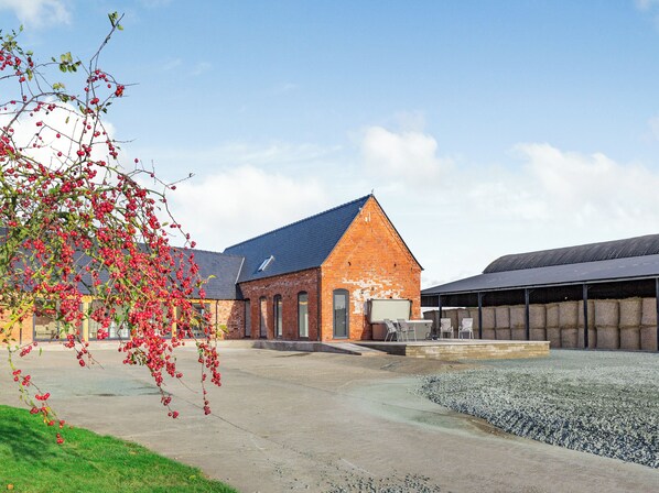 A building with a brick facade, a sloped roof, and a gravel area in front.