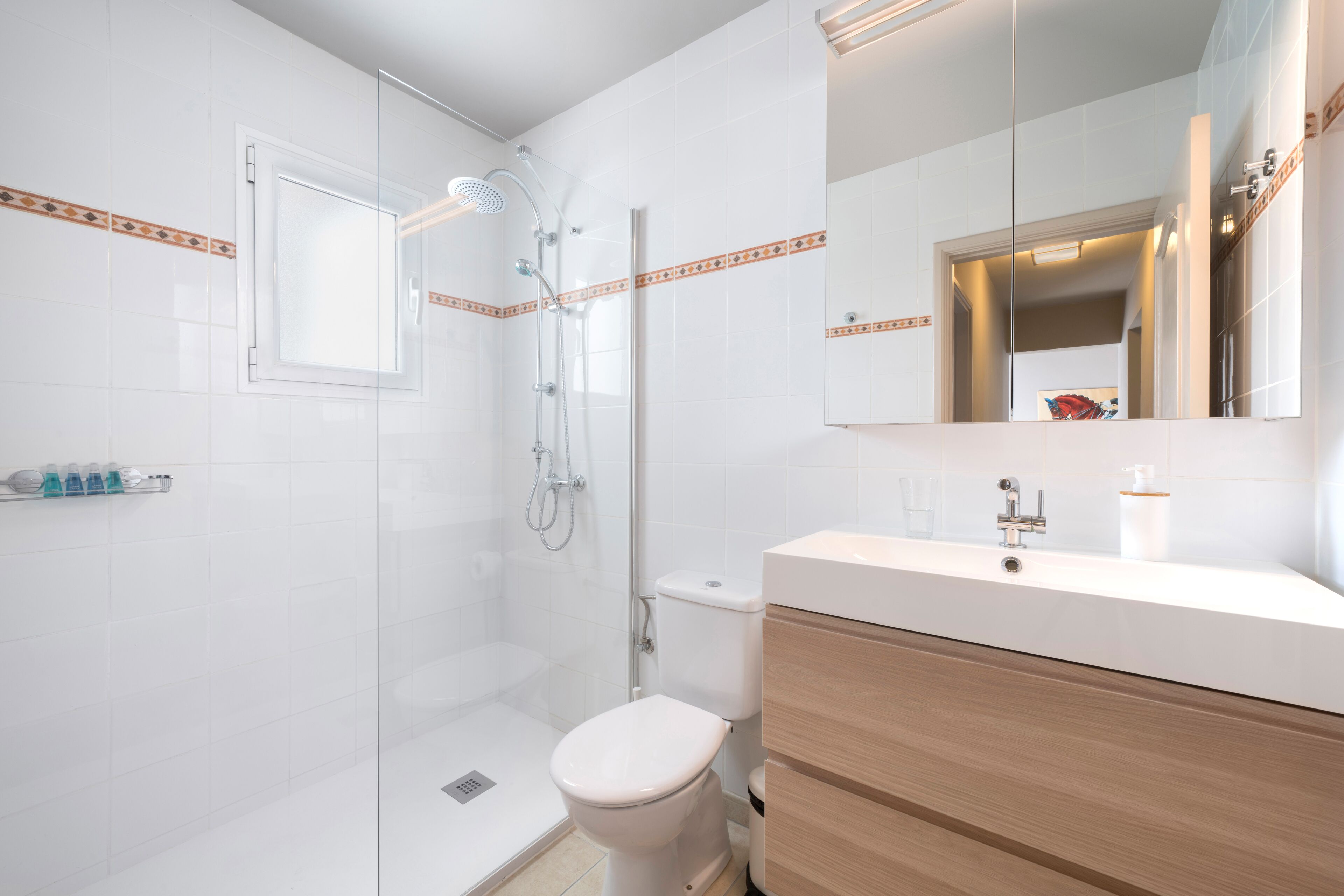 Een moderne badkamer met douche, toilet en wastafel.