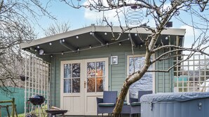 Ein kleines, eingeschossiges Gebäude mit Veranda, Whirlpool und Gartenmöbeln.