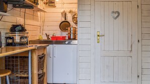Eine Küche mit einer Holztür, einem roten Topf und einem weißen Kühlschrank.
