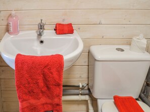 Un baño con lavamanos, inodoro y toallas rojas.