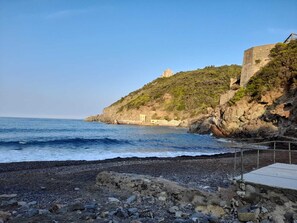 A rocky beach with a small building on a hill, overlooking the sea. - Iane's house (Quercianella)