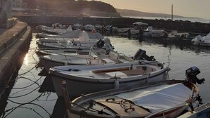 Ein Yachthafen mit mehreren dort liegenden Booten, bewölkter Himmel und untergehender Sonne im Hintergrund.