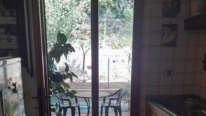 Eine Küche mit Holzausstattung, einer Arbeitsfläche und Blick auf eine Terrasse mit Stühlen und einem Tisch.