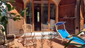 Eine sonnendurchflutete Terrasse mit Pool, Holzmöbeln und einer großen Schiebeglastür, die zu einem Innenbereich führt.