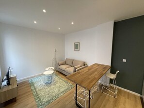Un salon moderne avec une table à manger en bois, un canapé et une petite table d’appoint.