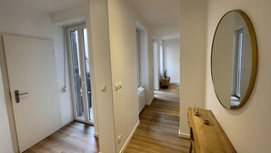 A hallway with wooden flooring, a wooden bench, and a large mirror on the wall. - Newly renovated apartment, a stone's throw from town center and station (Strasbourg)