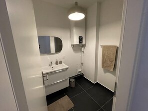 Une salle de bain moderne avec un lavabo blanc, un miroir et un porte-serviettes.