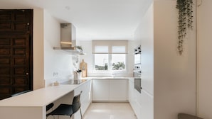 Una cocina moderna con armarios blancos, encimera negra y ventana que proporciona luz natural.