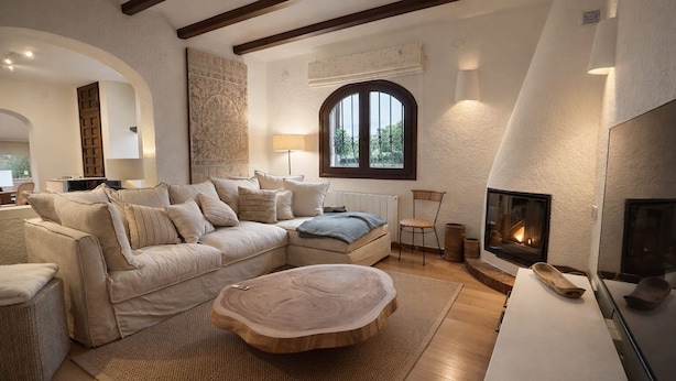 Un salón acogedor con un sofá modular, una mesa de centro de madera, una chimenea y un ventanal con vistas.
