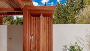 A wooden door with a showerhead, a concrete floor, and a small plant beside a white wall. - Oresteia Executive Villa, a Flamboyant Retreat (Tragaki)