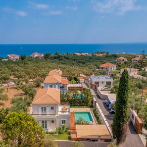 A residential area with houses, a swimming pool, and a view of the sea.