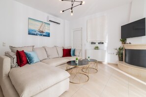 A modern living room with a beige sectional sofa, two round gold tables, a flat-screen TV, and a fireplace.
