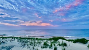 Een strand met duinen en uitzicht op de oceaan.