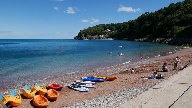 Una playa con kayaks alineados y gente relajándose.