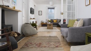 Una sala moderna con un sofá gris, una mesa de centro de madera y una alfombra estampada.