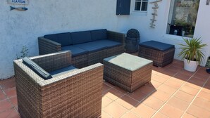 A patio with wicker furniture, a blue sofa, and a potted plant.