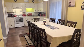 A dining area with a table, chairs, and a kitchen in the background.