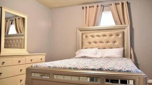 A bedroom with a bed, a dresser, and a mirror.