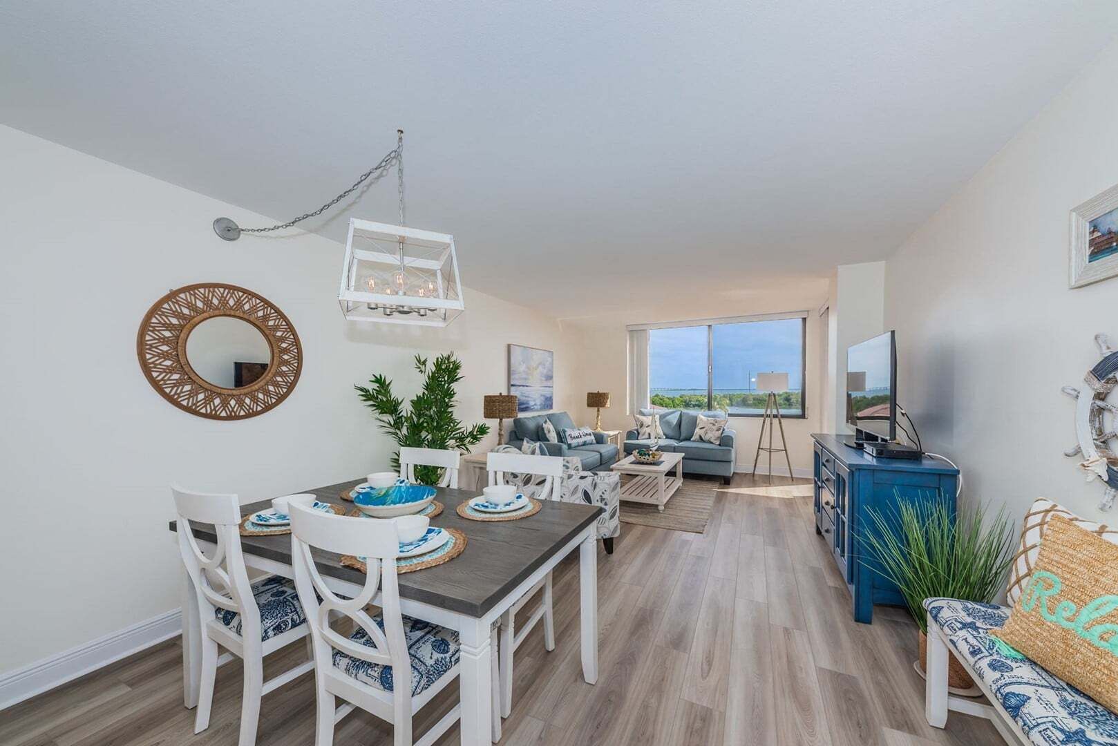 Una sala de estar moderna con comedor, un ventanal con vistas y un televisor sobre un mueble.