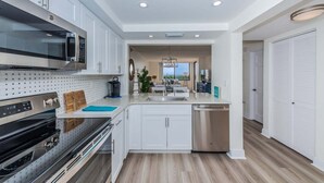 A modern kitchen with white cabinets, stainless steel appliances, and a wooden floor. - Waterview 1BR condo with pool, hot tub, and balcony in St. Petersburg. (St Petersburg)