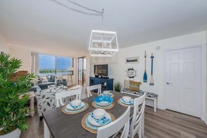 Een moderne woonkamer met een eethoek, grote ramen en uitzicht op het omliggende landschap.