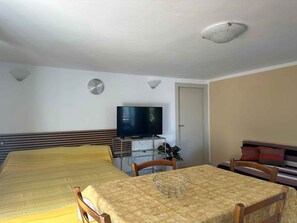 A room with two beds, a TV, a table with a wire basket, and a door. - Holiday apartment with pool and balcony (Jadranovo)