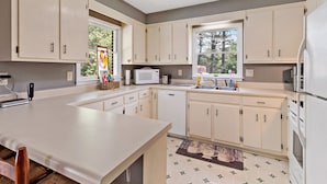 A modern kitchen with white cabinets, a large island, a microwave, and a dishwasher.