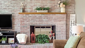 A living room with a brick fireplace, a television, and a cozy sofa.