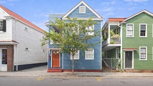 A row of three-story townhouses with a central tree, a red door, and a visible garage door. - Heart of Downtown - 1 Bedroom Suite w/ Parking! (Charleston)