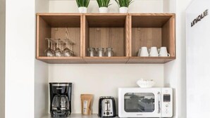 A compact kitchenette with a coffee maker, toaster, microwave, and shelves with glassware and plants. - Downtown Charmer! 3BD/3BA - 2 Blocks to King (Charleston)