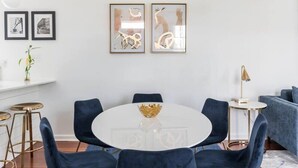 A dining area with a round table, six chairs, and a gold decorative bowl. There are framed pictures on the wall, a small plant, and a lamp on a side table. - Downtown Charmer! 3BD/3BA - 2 Blocks to King (Charleston)