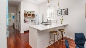 A modern kitchen with white cabinetry, a central island with stools, a microwave, and a gas stove. - Downtown Charmer! 3BD/3BA - 2 Blocks to King (Charleston)