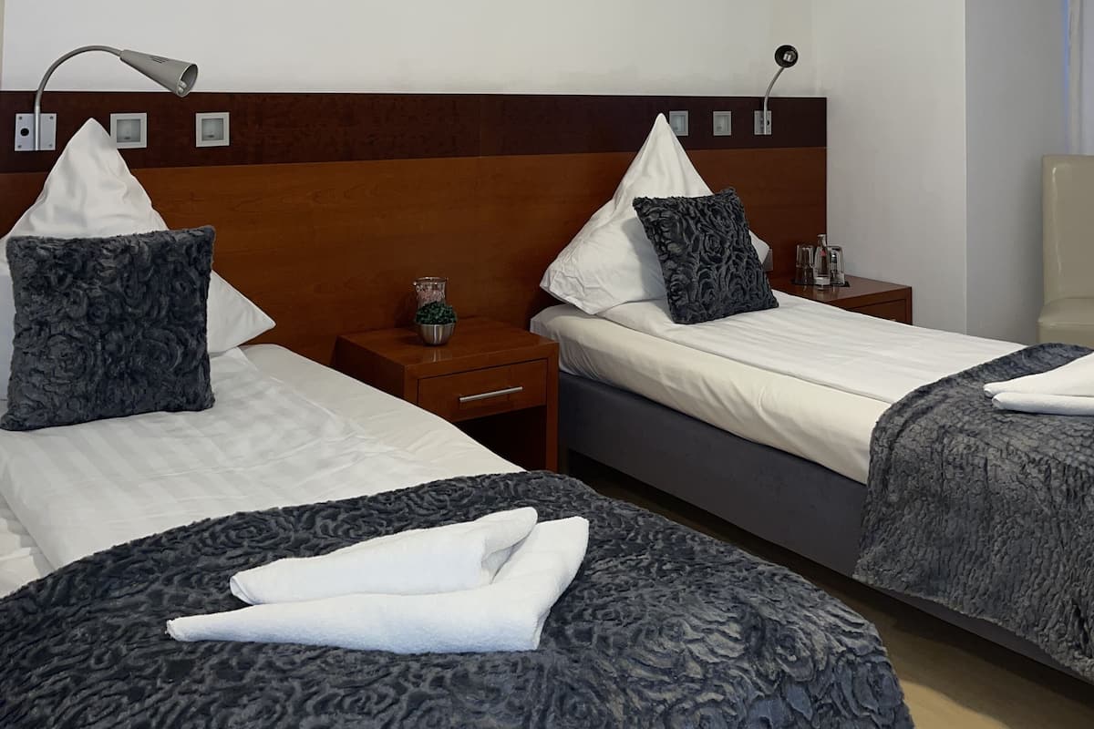 A hotel room with two beds, a wooden headboard, bedside tables with lamps, and a ceiling light.
