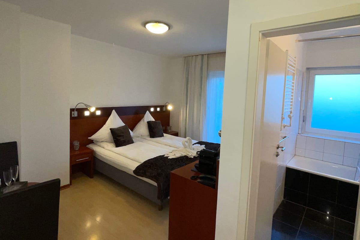 A hotel room with a bed, bedside table, and a desk with a chair.